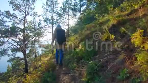 在阳光明媚的日子里一个戴着兜帽背着背包的女孩沿着陡峭的斜坡散步视频的预览图