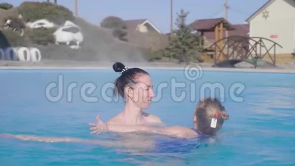 快乐的母女沐浴池边缘在一个自然的热SPA视频的预览图