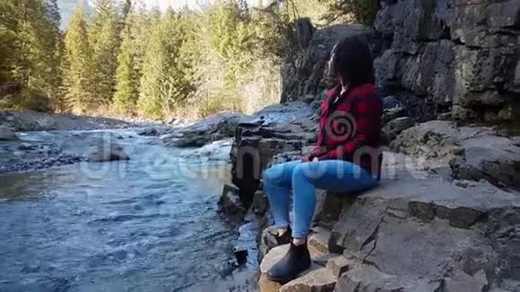 加拿大山景中坐在河边的女孩视频的预览图