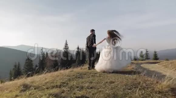 新婚夫妇白人新郎新娘在山坡上奔跑新婚夫妇视频的预览图