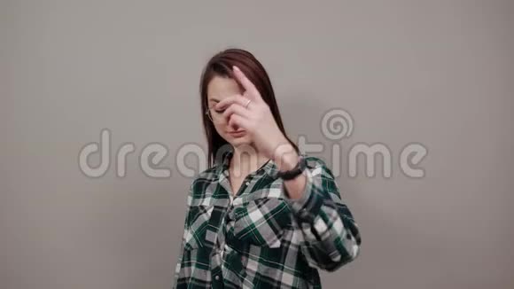 灰色背景的幸福女人戴着眼镜用手指做手势视频的预览图