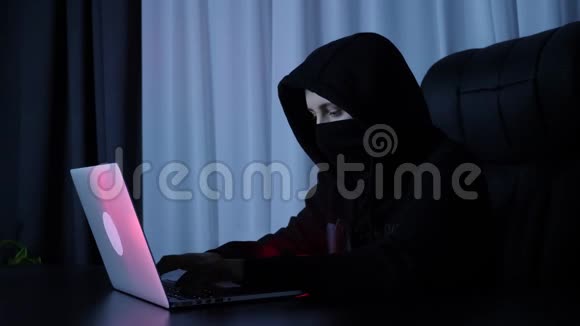 黑客在计算机上破坏在线安全保护女性在黑色面具和帽衫编码和编程笔记本电脑屏幕H视频的预览图