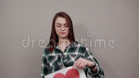 戴眼镜的玛特女人拿着一张红心纸想着视频的预览图