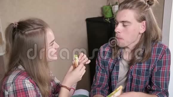 可爱的年轻夫妇坐在厨房里吃三明治微笑着特写视频的预览图