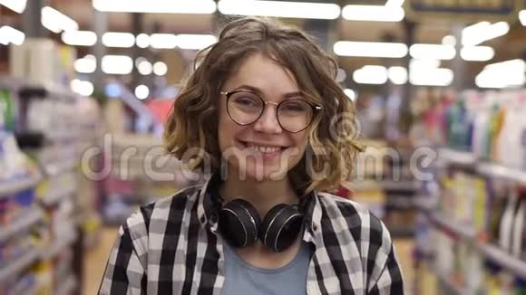 肖像年轻女子站在镜头前微笑着在超市感受快乐的女孩购物脸零售店视频的预览图
