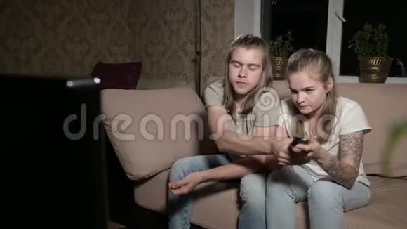 年轻夫妇正在看电视男人切换频道女人选择控制视频的预览图