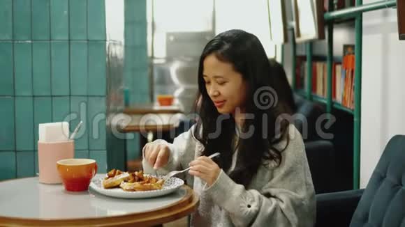 漂亮的亚洲女孩在餐馆咖啡馆吃蛋糕她微笑积极快乐视频的预览图