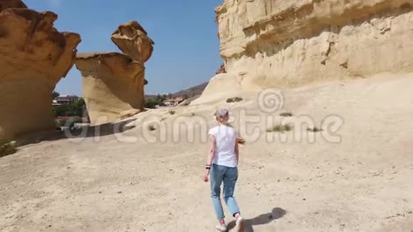 女孩走过沙漠附近黄色的未来主义岩石视频的预览图