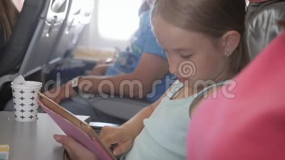 可爱的女孩乘飞机旅行在飞行中使用数字平板电脑与孩子一起出国旅行的概念视频的预览图