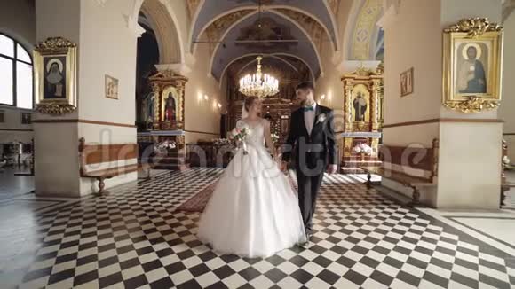 新婚夫妇白人新娘和新郎一起在一个古老的教堂里散步婚礼视频的预览图