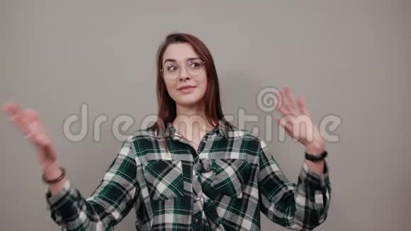 在灰色背景下戴眼镜的自信女人展示自己的双手视频的预览图