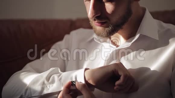 英俊的新郎把他的袖口用袖扣固定在夹克上商人视频的预览图