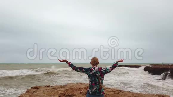 在暴风雨中女孩站在海边时举起双手视频的预览图