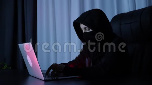 黑客在计算机上破坏在线安全保护女性在黑色面具和帽衫编码和编程笔记本电脑屏幕H视频的预览图
