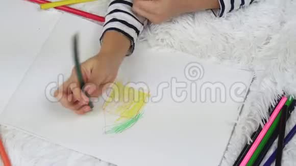 一个快乐的孩子躺在房子的地板上用铅笔画房子儿童的休闲家庭和儿童视频的预览图