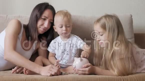 妈妈和两个孩子把钱存到储蓄罐里家庭为未来赚钱投资概念视频的预览图