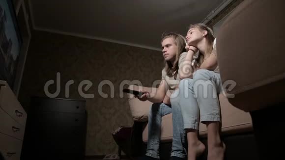 这对年轻夫妇正在看电视女人切换频道男人选择控制视频的预览图