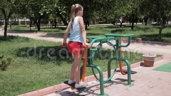 夏天在公园里女孩在街头运动设备上进行锻炼视频的预览图