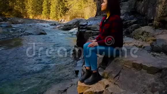 加拿大山景中坐在河边的女孩视频的预览图