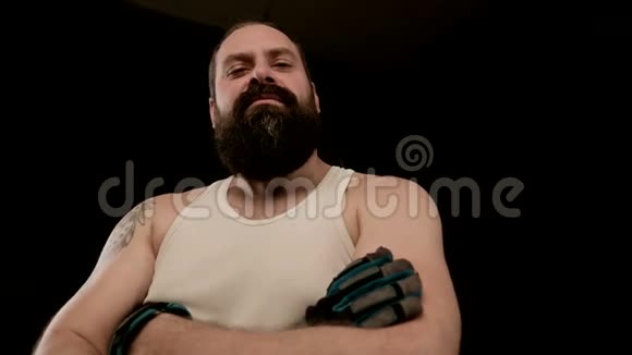 蓄胡子的男人在黑色的背景上交叉双臂做愤怒的鬼脸特写视频的预览图