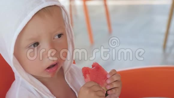 可爱的男孩在海滩的咖啡馆里吃西瓜视频的预览图