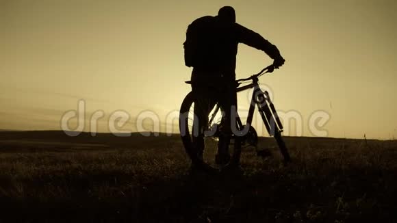 日落时骑自行车的山地自行车者的剪影运动旅行和积极的生活理念视频的预览图