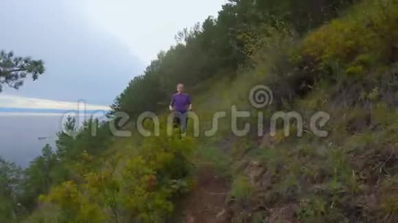 女孩沿着海岸陡峭斜坡的小径奔跑视频的预览图