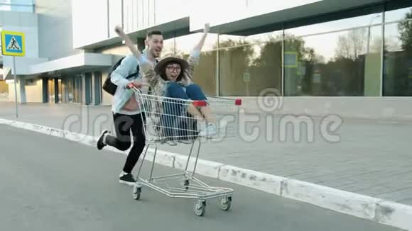 在现代都市中快乐的情侣们骑着购物车玩得很开心视频的预览图