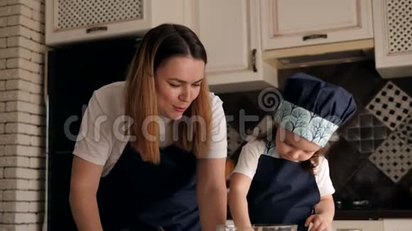 小可爱的女孩一边吃面团一边在家里厨房做饼干视频的预览图