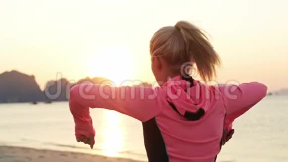 年轻女子在海滩上锻炼的后景视频的预览图