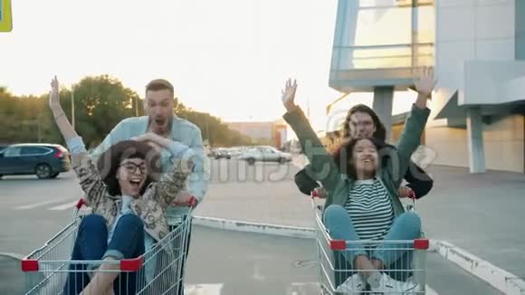 在城市的停车场里男人和女人都会骑着购物车开心地笑视频的预览图