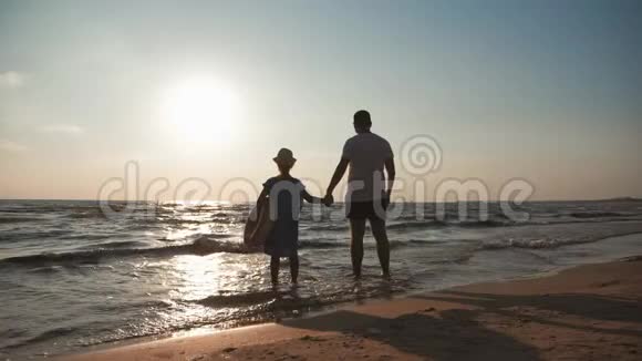 剪影父女在日落时在海滩上玩耍友好家庭旅游生活方式的概念视频的预览图