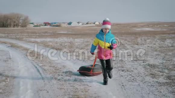 年轻女孩骑在一座小山上的充气雪管上视频的预览图