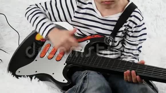 一个学龄前儿童花时间为孩子们演奏一把小电吉他这孩子摸着吉他的琴弦视频的预览图