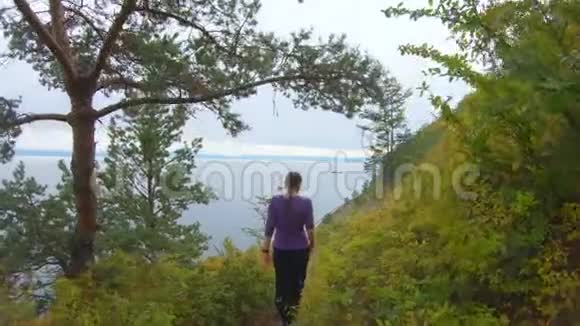 秋天女孩沿着海岸陡峭的斜坡沿着小径爬下去视频的预览图