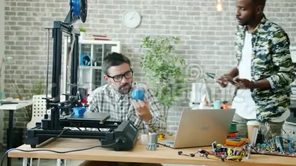 同事用3d打印机平板电脑和笔记本电脑在办公室交谈视频的预览图