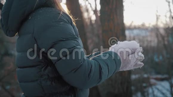 一个快乐的小女孩在一个美丽的冬天玩雪背景上的飞雪冬季概念视频的预览图