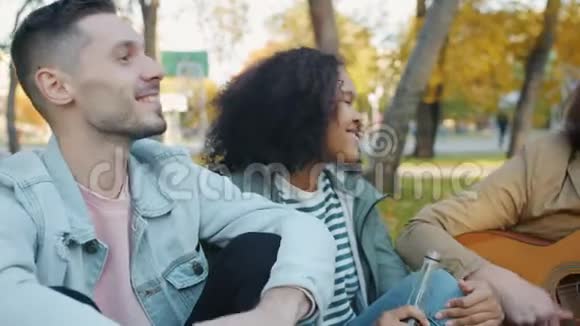 秋天城市公园里快乐的年轻人弹吉他的画像视频的预览图