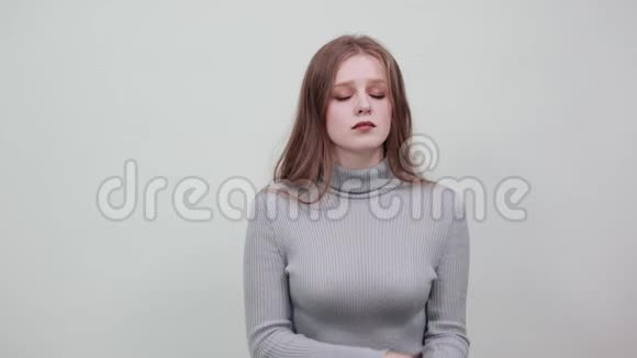 一位身穿灰色毛衣的年轻红发女子轻轻地闭上了眼睛视频的预览图