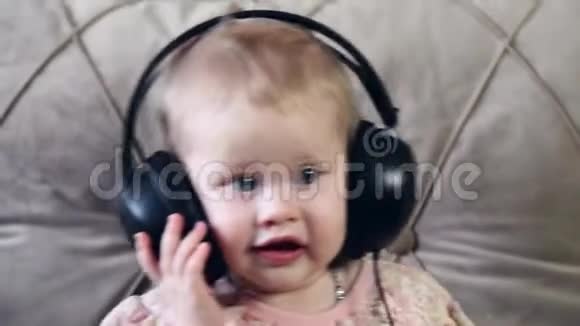 一个小女孩坐在沙发上用耳机听音乐视频的预览图