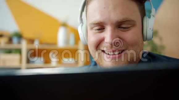 微笑的学生戴着耳机享受音乐在公寓里使用平板电脑视频的预览图