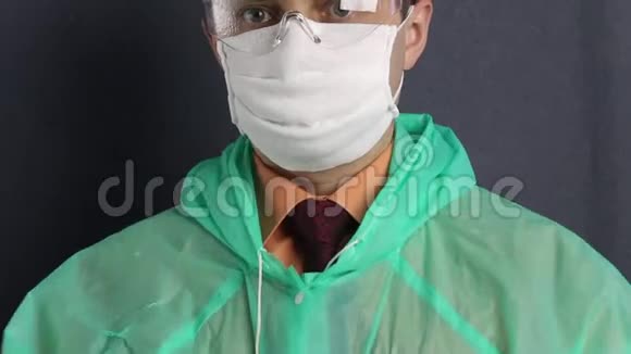 一个穿着保护外套戴着纱布口罩脸上戴着眼镜的人他戴上兜帽系紧它病毒防护视频的预览图