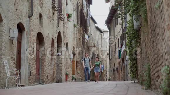 一对情侣穿着便装牵着手走在老城区狭窄的街道上视频的预览图