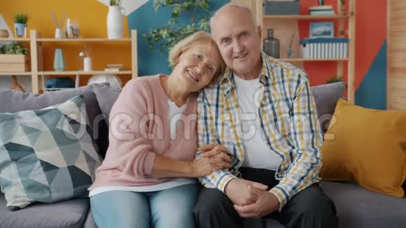 老人男女幸福夫妇坐在沙发上微笑的画像视频的预览图