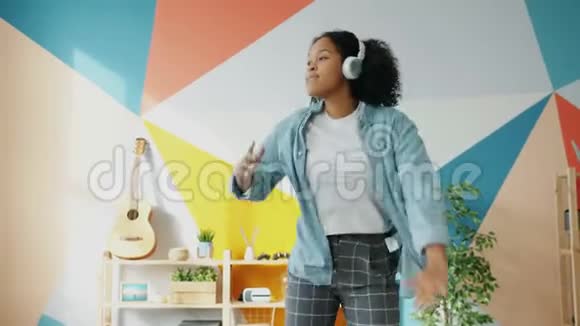 快乐的非裔美国学生戴着耳机在家跳舞快乐视频的预览图