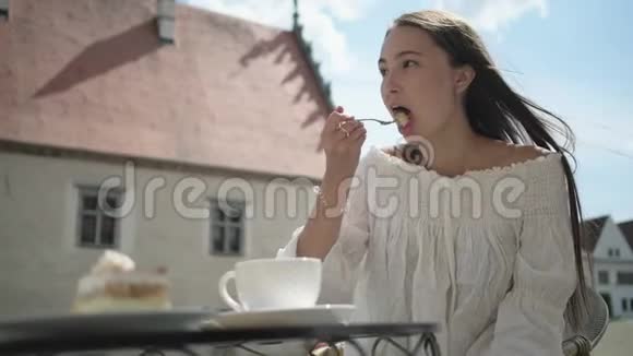 女人在露天露台上吃蛋糕喝咖啡视频的预览图