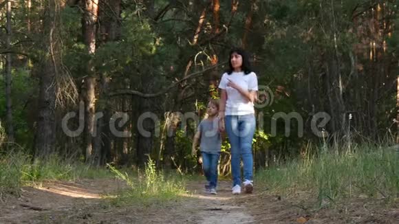 一个幸福的家庭在森林里散步享受大自然妈妈牵着儿子手跟他说话生活方式爱和爱视频的预览图