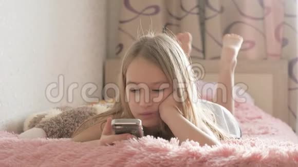 好奇的女孩使用手机应用程序看手机设备坐在床上儿童和小工具的概念视频的预览图