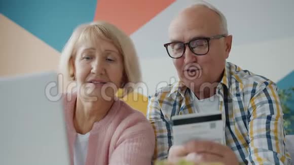 幸福的老年夫妇用信用卡在线购物视频的预览图