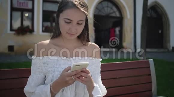 漂亮女人坐在户外打手机短信视频的预览图